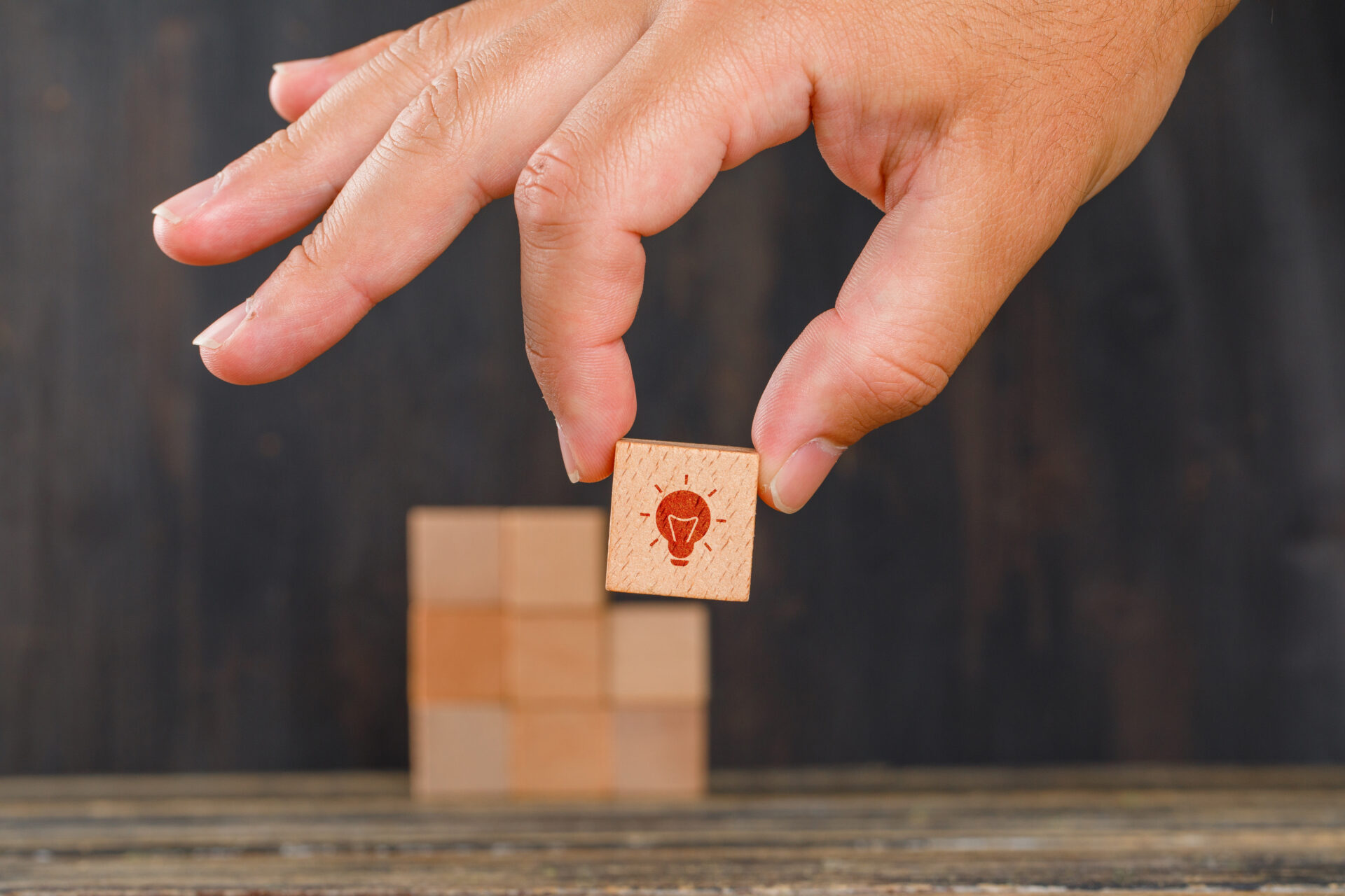 Hand holding a wooden cube symbolising innovation and implementation